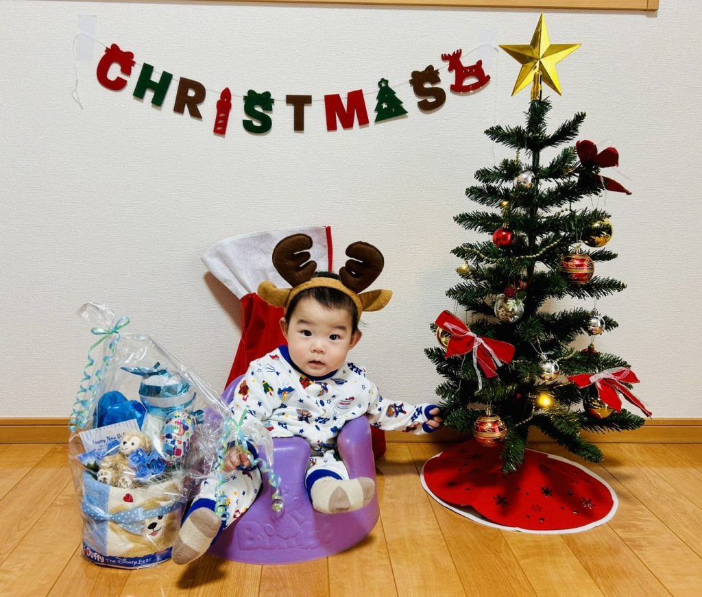 婚活卒業生の7ヶ月の赤ちゃん。クリスマスツリーの横でトナカイ姿をした可愛らしい赤ちゃんの写真。結婚相談所T&Hベストパートナーの成婚後の幸せな家族の様子。